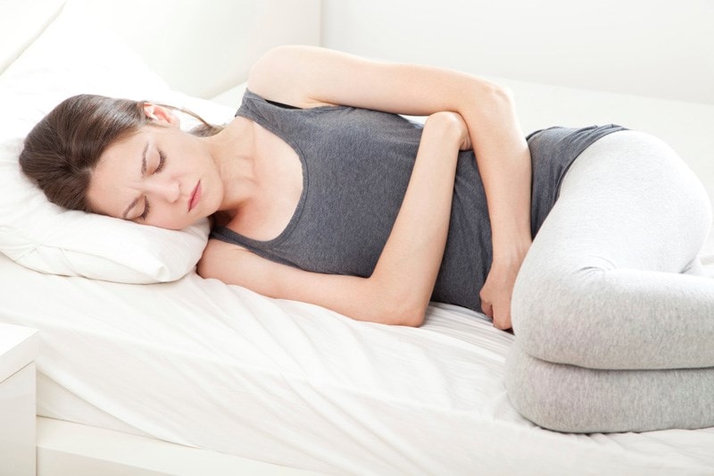 woman lying on her side holding tummy